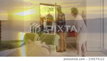 Greeting masked hosts and visitor holding bouquet at open front door in living room, warm sunlight 139574122