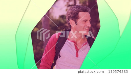 Standing man wearing red-gray-henley and backpack in park framed by green cutouts, blurred trees Standing man wearing red-gray-henley and backpack in park framed by green cutouts, blurred trees 139574283