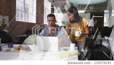 Working colleagues in collared shirt, yellow blouse, pointing at laptop in open office, with plant Working colleagues in collared shirt, yellow blouse, pointing at laptop in open office, with plant 139574285