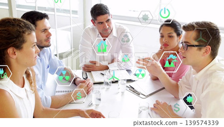 Meeting team of six in business-casual around office table with laptop, viewing AR energy icons Meeting team of six in business-casual around office table with laptop, viewing AR energy icons 139574339