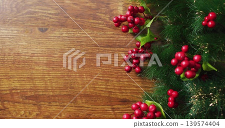 Displaying pine sprig resting on wood table with red berries green leaves gold tinsel, copy space 139574404
