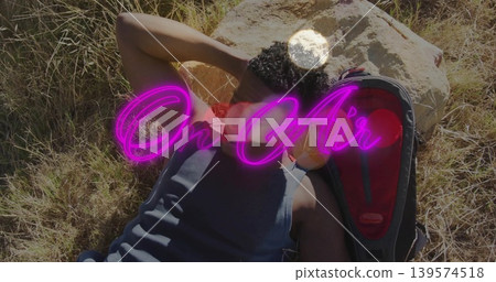 Reclining man wearing tank top on grass by pale rock, red-lined backpack, magenta On Air overlay Reclining man wearing tank top on grass by pale rock, red-lined backpack, magenta On Air overlay 139574518