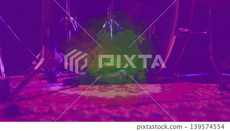 Framing bass drum and pedal with foot in dark shoe pressing on patterned rug, magenta lights Framing bass drum and pedal with foot in dark shoe pressing on patterned rug, magenta lights 139574554