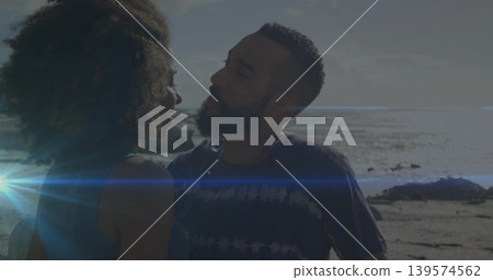 Embracing couple leaning at rocky shoreline with ocean horizon, sun flare, tank top and tie-dye tee Embracing couple leaning at rocky shoreline with ocean horizon, sun flare, tank top and tie-dye tee 139574562
