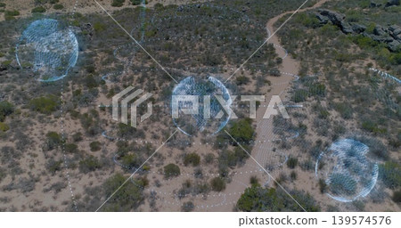 Hovering aerial arid scrubland revealing three blue holographic spheres over winding dirt trail Hovering aerial arid scrubland revealing three blue holographic spheres over winding dirt trail 139574576