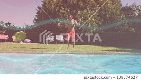 Leaping shirtless man lifting arms at swimming pool edge, with red trunks and picnic setup Leaping shirtless man lifting arms at swimming pool edge, with red trunks and picnic setup 139574627