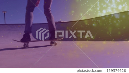 Skating skater in cuffed jeans and dark shoes carving skatepark bowl with board and light particles Skating skater in cuffed jeans and dark shoes carving skatepark bowl with board and light particles 139574628