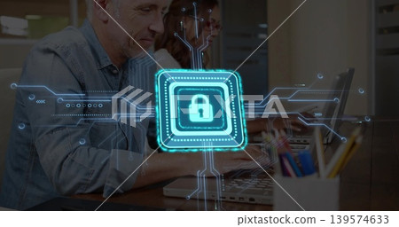 Typing man in denim and woman in glasses at office desk with laptops and padlock overlay Typing man in denim and woman in glasses at office desk with laptops and padlock overlay 139574633