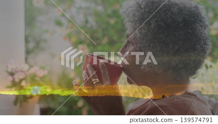 Sipping senior African-American woman in rose-top on porch, holding mug, sunset overlay, copy space 139574791