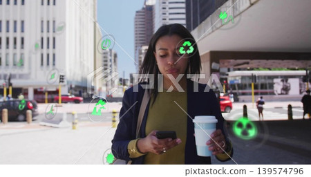 Walking woman in navy blazer holding coffee cup checking phone in downtown plaza with green icons Walking woman in navy blazer holding coffee cup checking phone in downtown plaza with green icons 139574796