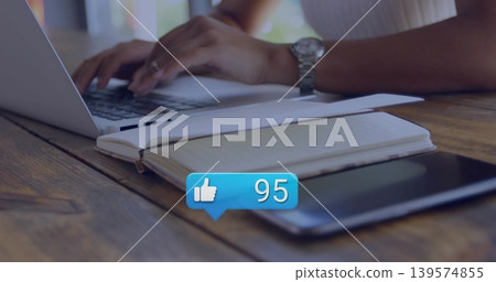 Typing female hands in ribbed top on wooden cafe table with laptop notebook tablet alert bubble 139574855