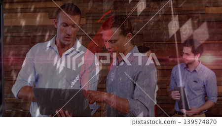 Working two men in shirts holding laptop, pointing at screen in office with folder, mug, overlays 139574870
