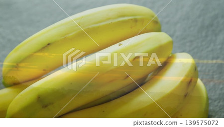 Filling frame, bunch of ripe yellow bananas resting on textured gray counter, reflecting light 139575072