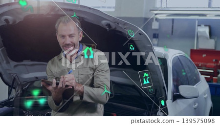 Leaning mechanic in coveralls holding tablet checking white car at workshop, showing green icons Leaning mechanic in coveralls holding tablet checking white car at workshop, showing green icons 139575098