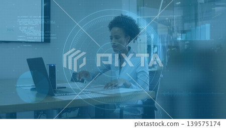 Reviewing papers, typing on laptop, woman in white shirt in open-plan office with pen HUD overlay Reviewing papers, typing on laptop, woman in white shirt in open-plan office with pen HUD overlay 139575174