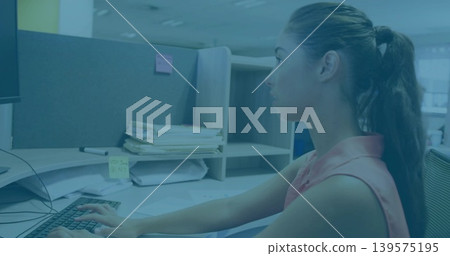 Typing woman ponytail wearing sleeveless top at cubicle, with monitor and keyboard, copy space Typing woman ponytail wearing sleeveless top at cubicle, with monitor and keyboard, copy space 139575195