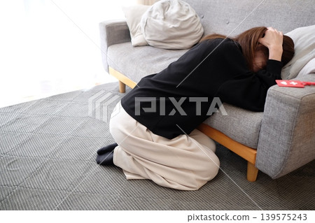 A woman troubled by her cluttered living room 139575243