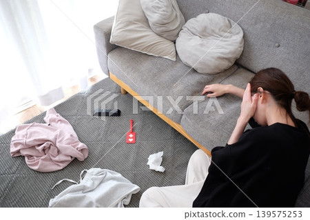 A woman troubled by her cluttered living room A woman troubled by her cluttered living room 139575253