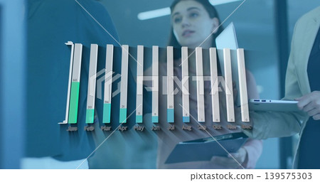 Showing 3D bar chart with green Jan Feb in glass room, blazer-clad team holding tablet laptop Showing 3D bar chart with green Jan Feb in glass room, blazer-clad team holding tablet laptop 139575303