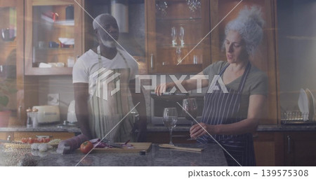 Pouring woman in striped apron pouring wine from bottle into glass in home kitchen, cutting board Pouring woman in striped apron pouring wine from bottle into glass in home kitchen, cutting board 139575308