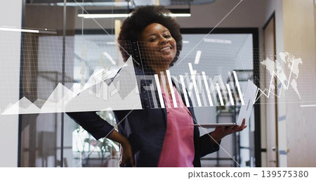 Analyzing analyst in dark blazer pink blouse in office hallway, holding slim laptop with AR charts Analyzing analyst in dark blazer pink blouse in office hallway, holding slim laptop with AR charts 139575380