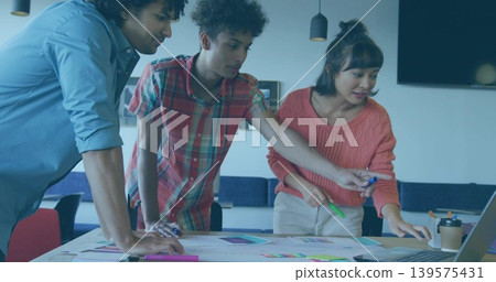 Leaning coworkers wearing coral, plaid and light blue clothing, examining charts and laptop in room Leaning coworkers wearing coral, plaid and light blue clothing, examining charts and laptop in room 139575431