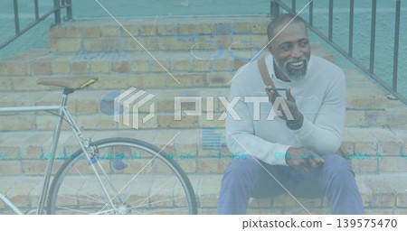 Sitting man speaking into smartphone on brick steps, with bicycle, charts, gray sweater, copy space Sitting man speaking into smartphone on brick steps, with bicycle, charts, gray sweater, copy space 139575470