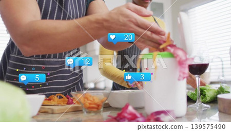 Peeling couple in aprons using peeler over peel bin at home kitchen with reaction icons Peeling couple in aprons using peeler over peel bin at home kitchen with reaction icons 139575490