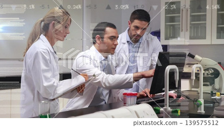 Pointing male and female researchers in lab coats working at bench computer, with microscope Pointing male and female researchers in lab coats working at bench computer, with microscope 139575512