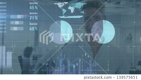 Smiling man in light shirt standing near center of open office, with data charts Smiling man in light shirt standing near center of open office, with data charts 139575651