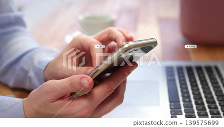 Tapping smartphone, adult hands in blue dress shirt operating laptop on wooden desk, ceramic mug Tapping smartphone, adult hands in blue dress shirt operating laptop on wooden desk, ceramic mug 139575699
