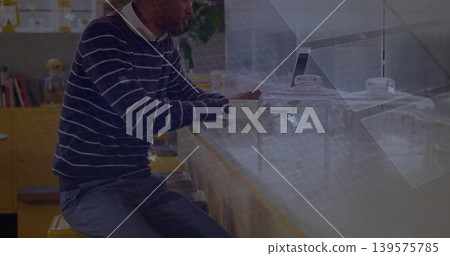 Working man wearing striped sweater and collared shirt typing on laptop at cafe counter, with mug Working man wearing striped sweater and collared shirt typing on laptop at cafe counter, with mug 139575785