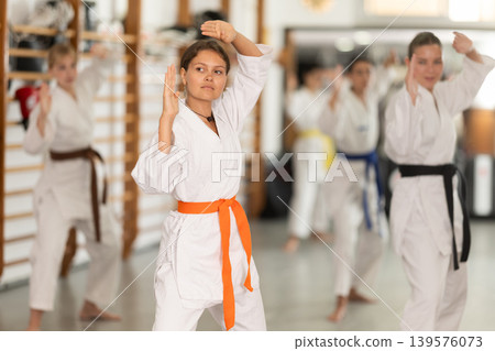 Women students repeat position and perform sequence of punches and painful techniques kata Women students repeat position and perform sequence of punches and painful techniques kata 139576073