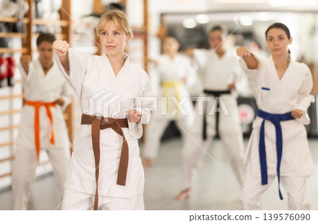 Women students repeat position and perform sequence of punches and painful techniques kata 139576090