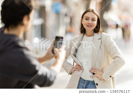 Man takes photo of cheerful woman on a street in spring city 139576117
