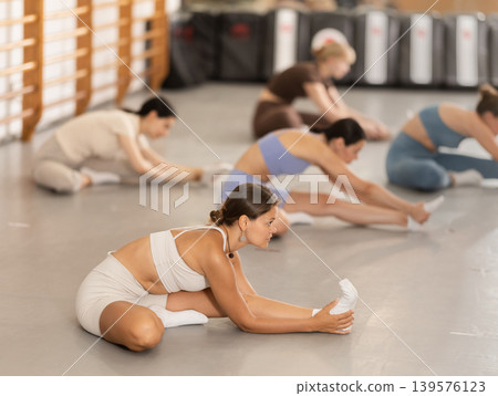 Young girl doing leg stretching in group Young girl doing leg stretching in group 139576123