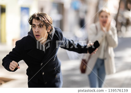 Male thief trying to snatch mobile phone of frightened woman on city Male thief trying to snatch mobile phone of frightened woman on city 139576139