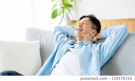 A man relaxing while leaning back on a sofa. A man relaxing while leaning back on a sofa. 139576158