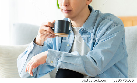 一個男人一邊喝咖啡一邊思考。 一個男人一邊喝咖啡一邊思考。 139576160
