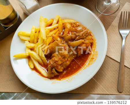 Pork trotters stewed in tomato gravy with fries Pork trotters stewed in tomato gravy with fries 139576212