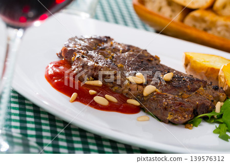 Beef steak served with ketchup, baked potatoe and pine nuts 139576312