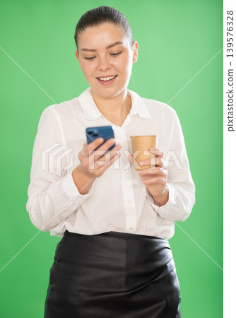 Young girl on green screen background with coffee is typing text message Young girl on green screen background with coffee is typing text message 139576328