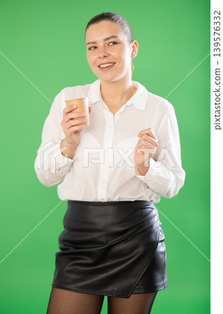 Chroma key compositing. Pretty young woman drinking coffee against green chroma key background Chroma key compositing. Pretty young woman drinking coffee against green chroma key background 139576332