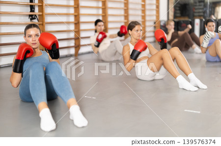 women doing abdominal exercise in boxing gloves women doing abdominal exercise in boxing gloves 139576374