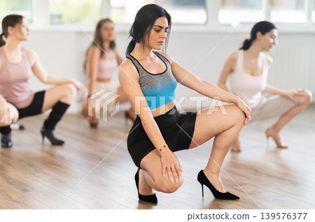 Armenian girls perform dance in heels, squat down, actively repeat movements of instructor. Armenian girls perform dance in heels, squat down, actively repeat movements of instructor. 139576377