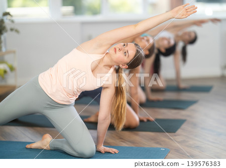 Young girl practicing Gate Pose during group yoga session 139576383