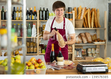Guy employee sells alcohol drink wine, and offers wide range of snack, nutrition. 139576385