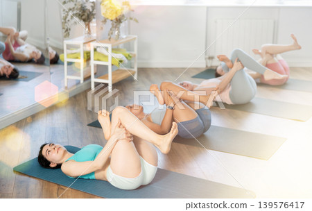 Girl teaches yoga lesson, shows students technique of performing Supt kapotasana asana 139576417
