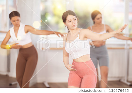 Teenage girl participating in beginner group ballet class 139576425