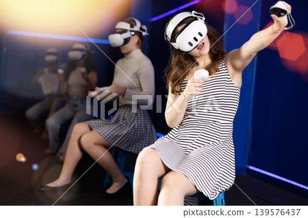 Expressive girl in VR goggles having fun in virtual reality room 139576437